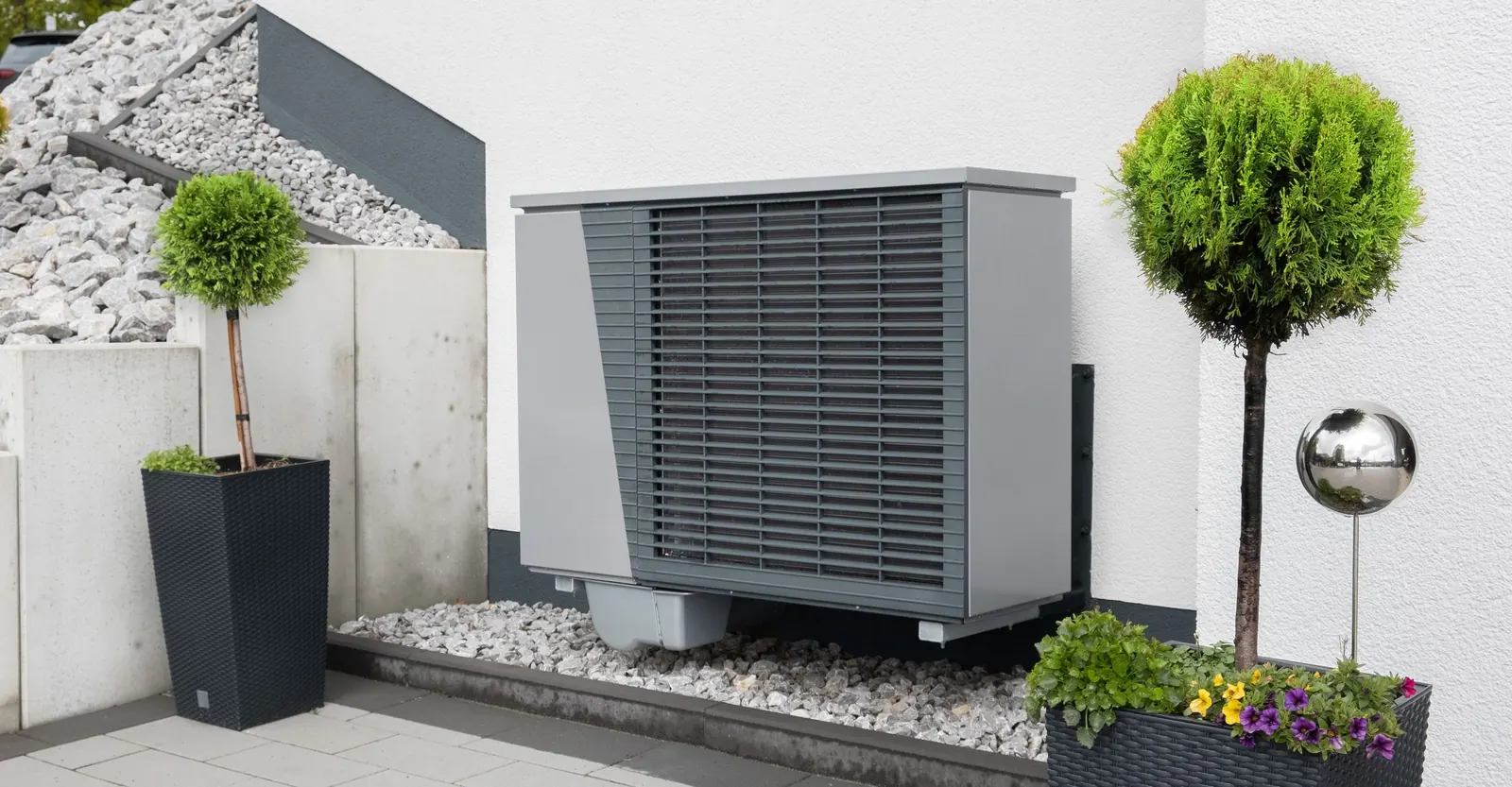 Pompa di calore all'esterno di una casa, su un letto di sassi bianchi